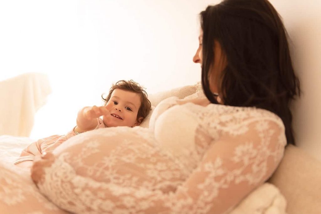 Maman enceinte tenant son enfant en souriant